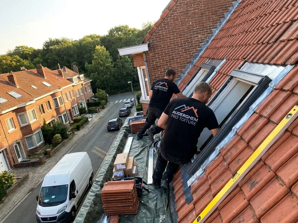 Couvreurs raccordant une fenêtre de toit dans une toiture en tuiles rouges