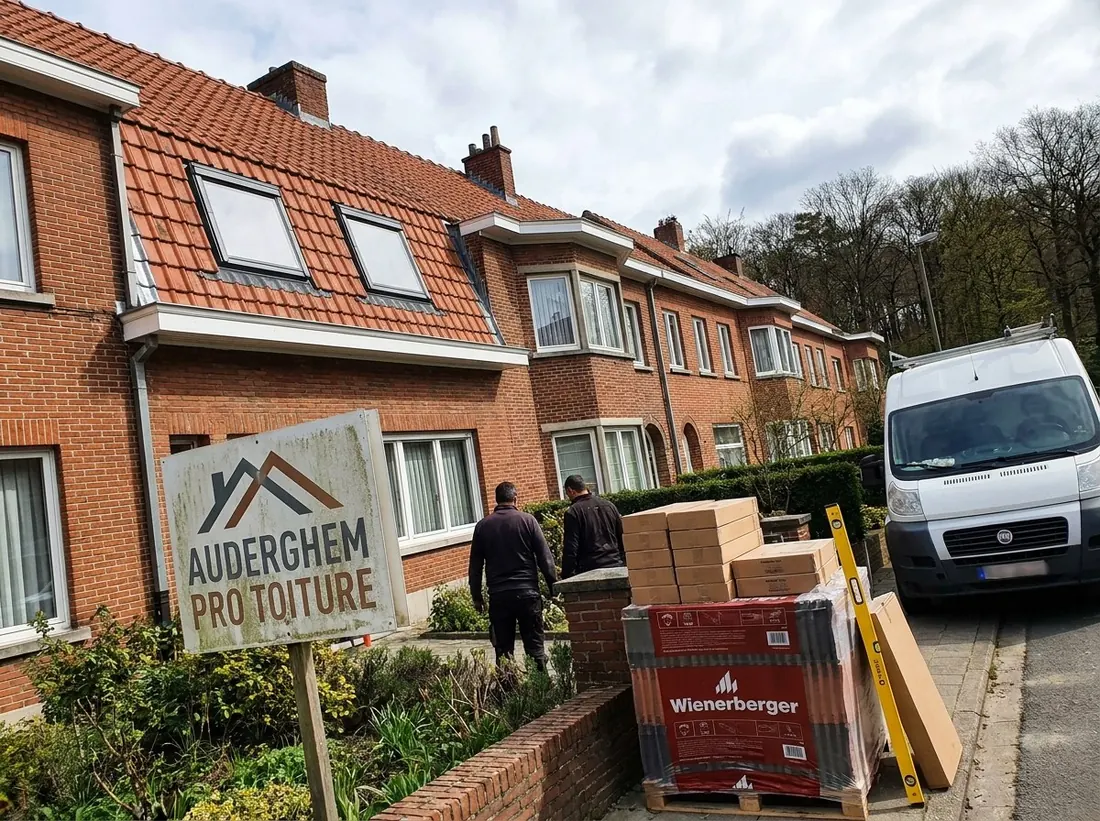 Panneau Auderghem Pro Toiture devant une maison en travaux, palettes de tuiles