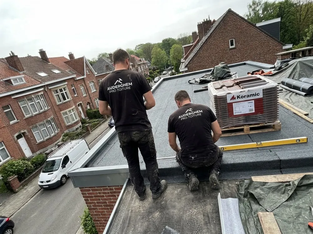 Deux couvreurs sur un toit plat, rouleaux d’étanchéité et niveau